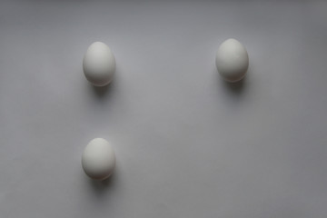 Три куриных яйца на светлом фоне