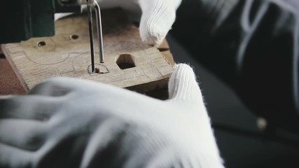 hands in white gloves jigsaw to cut a wooden workpiece, the symbol of bitcoin