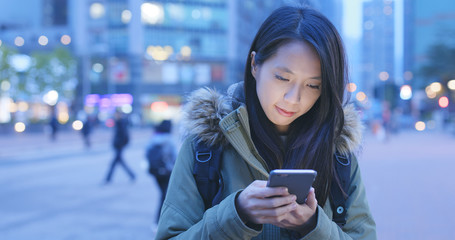 Woman use of cellphone in city at night