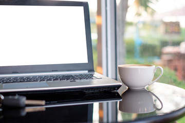White display laptop with coffee cup on glass table