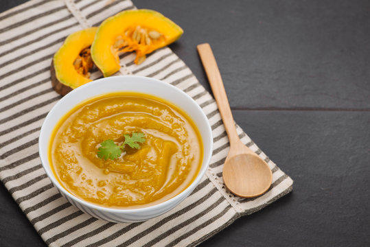 Pumpkin soup in a bowl with garlic and parsley herbs