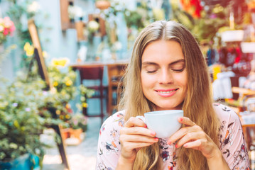 Beautiful woman is enjoying a cup of coffee in the cafe