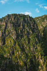 Obraz premium Green rocky cliff from below