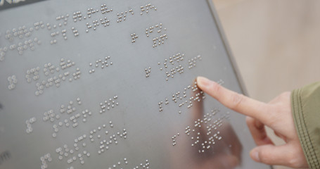 Blind reading on Braille at outdoor directory - obrazy, fototapety, plakaty