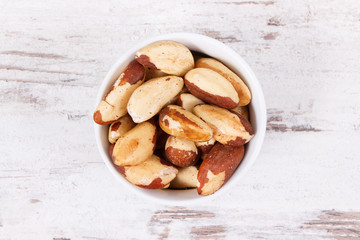 Brazil nuts in glass bowl on rustic board