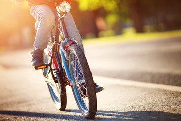 Naklejka premium child on a bicycle at asphalt road in early morning. Boy on bike in the city