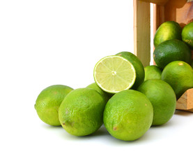 fresh lemons and lime fruits and some cut ones in a wooden box on a white background