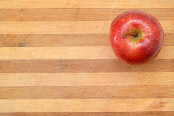 Red apple sit on a worn butcher block cutting board
