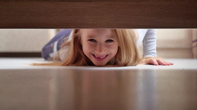 Little girl looks under the bed.