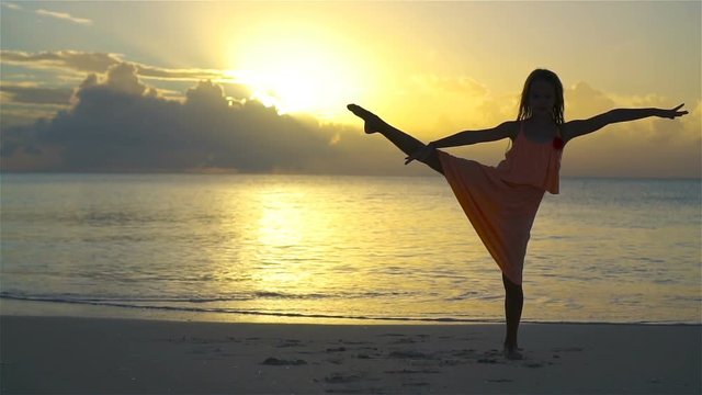 Silhouette of adorable little girl on white beach at sunset. SLOW MOTION