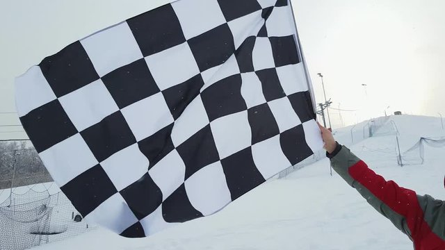 Male had holds the waving finish flag at ski slope background