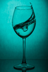 Splash of water in a wine glass on a green background