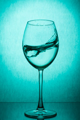 Splash of water in a wine glass on a green background