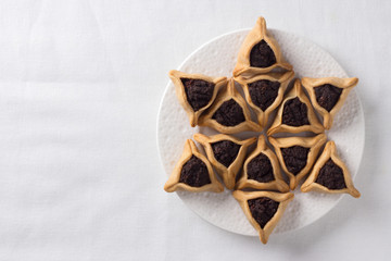 Traditional sweets for Jewish holiday of Purim. Hamantashen cookies or Aman ears, triangular cookies with poppy seeds, free space, top view