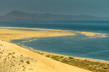 Big beach with yellow sand and blue water on Fuerteventura Risco del Paso