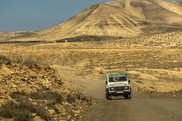 Fototapeta na wymiar A car drives through a sand desert on Fuerteventura