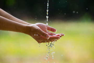 Water pouring in woman hand on nature background environment issues.Health care concept.
