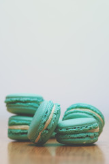 Blue pastel macaroons on wooden table. French almond cookies. Toned image.
