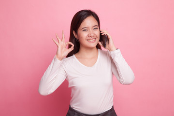 Fototapeta na wymiar Young Asian woman show with phone gesture and OK sign.