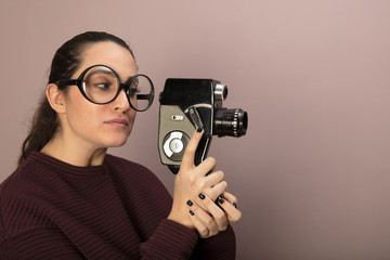 Woman wearing big glasses holding old vintage film camera