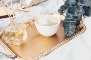 Gold tray with coffee and eucalyptus. Styled luxury morning
