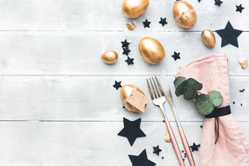 Rustic easter table setting with gold eggs. Top view
