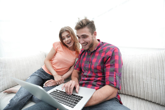 Happy modern couple surfing the net and working on laptop at home