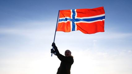 Woman with norway flag on the top point. Succesful winer consept