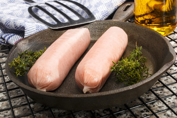 raw british sausages with herbs in a cast iron pan