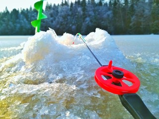 Small fishing rod at the edge of the hole waiting for the nibble