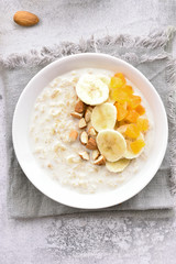 Oatmeal porridge with banana slices, almond and dried apricot