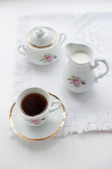 Cup of coffee, creamer on color wooden background