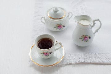 Cup of coffee, creamer on color wooden background