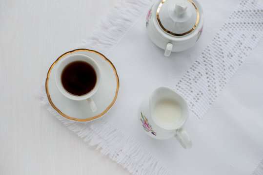 Cup of coffee, creamer on color wooden background