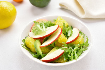 Fruit vegetable salad with red apples, avocado, orange slices