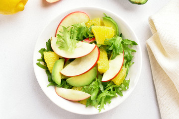 Fruit vegetable salad with red apples, avocado, orange slices