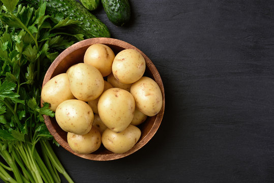 Raw potatoes in wooden bowl