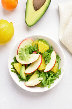 Fruit vegetable salad with red apples, avocado, orange slices