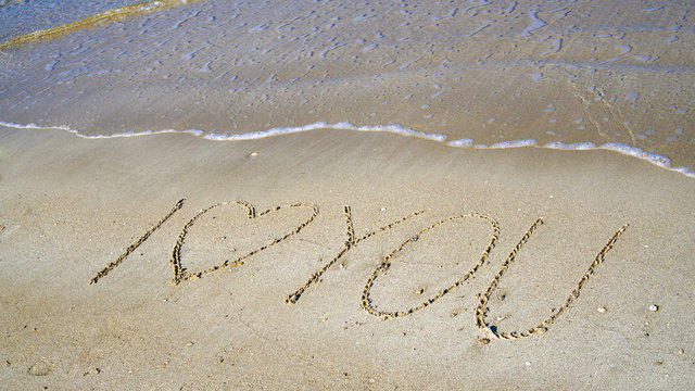 The inscription "I love you" on the sand near the sea