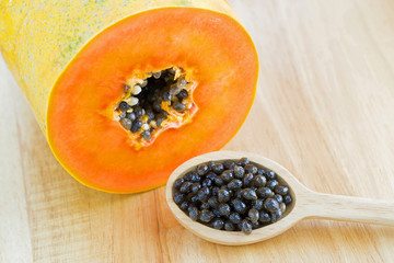 Fresh papaya seeds next to cut papaya fruit showing orange texture.