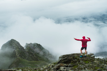 A hiker celebrating and striking a pose on the summit of a mountain top