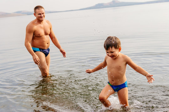 father and child playing on the lake. man with child playing in the water on the beach, emotional photos