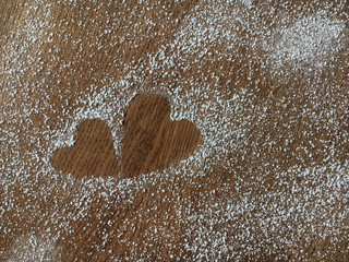 Close-up of two hearts made from sugar powder on the wooden table background