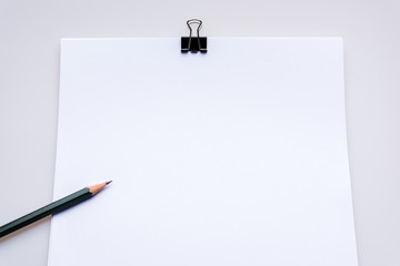 Copy space blank paper A4 and pencil and back binder clip on table white background ,top view