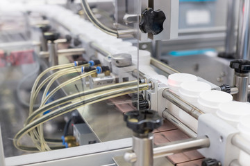 Medicine packaging on a production line. Pharmaceutical manufacturing. Plastic. Medicine bottles on assembly line.