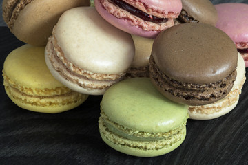 Macarons de couleurs différentes en tas sur fond noir
