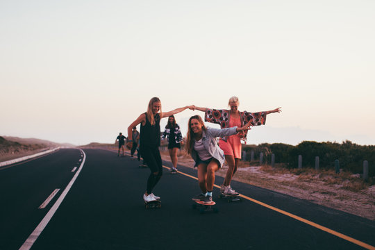 Happy group of friends riding skateboards together and having fun