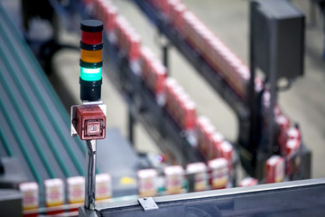 Green light showing production line in background is working properly. Manufacturing production line flowing with products with a green light showing everything is working properly.