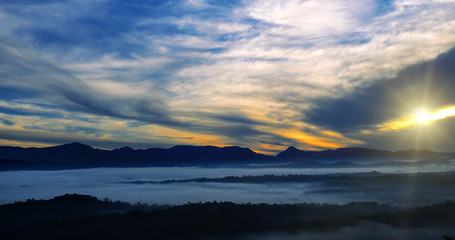 Fototapeta premium Mountain range with visible silhouettes through the morning colorful fog. Wide photo.