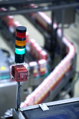 Green light showing production line in background is working properly. Manufacturing production line flowing with products with a green light showing everything is working properly.